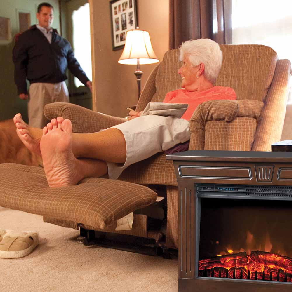 A woman relaxing in her easy-chair with an Amish Fireplace next to her